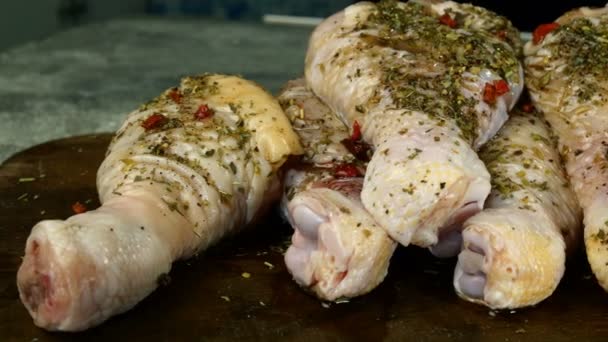 Rohe, mit Gewürzen und Kräutern bestreute Hühnerkeulen zum weiteren Kochen liegen übereinander. Nahaufnahme. — Stockvideo