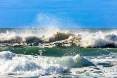 Photograph of waves from the Tasman Sea crashing onto Jones Beach against a blue sky near the town of Kiama Downs in the Illawarra region on the south coast of NSW, Australia.