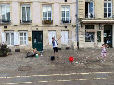 Caen, Fransa Ağustos 2020. Borsada sabun köpükleri, mutlu küçük kız uçan baloncuklar yakalar