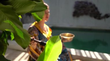 Renkli atlas kimono elbiseli hamile güzel bir kadın. Yaz terasında oturmuş çan çalıyor. 
