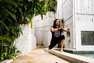 Yakışıklı adam yaz terasında yüzme havuzunun yanında yoga yapıyor.  