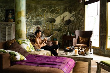 Çekici adam kanepede oturuyor ve yaz bungalovunda çay içiyor.