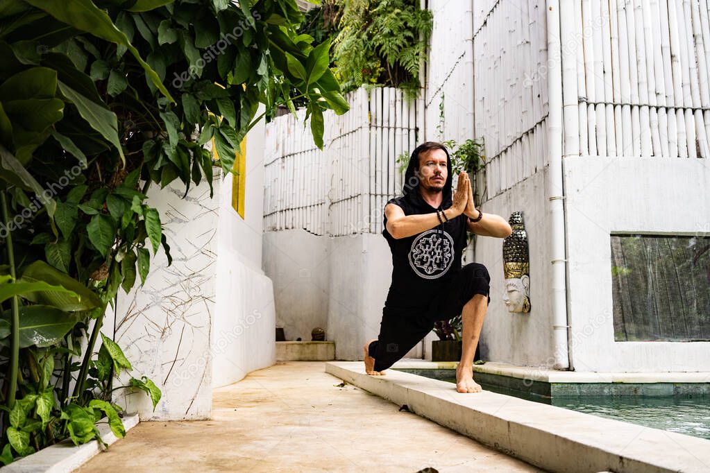 handsome man practice yoga in summer terrace near swimming pool  
