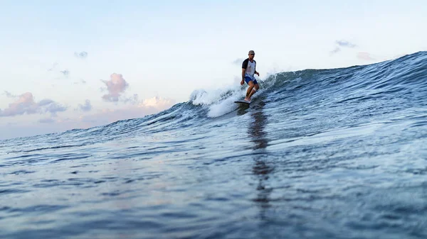 Young man swimming on surfing board in ocean in Bali, Indonesia.