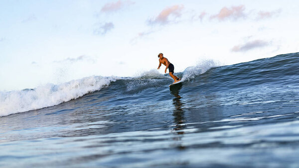 Young man swimming on surfing board in ocean in Bali, Indonesia.