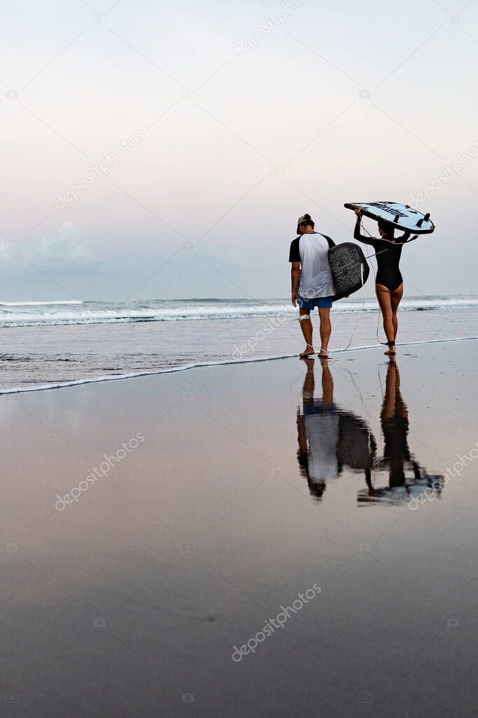 Young surfers walking on the beach in Bali, Indonesia.