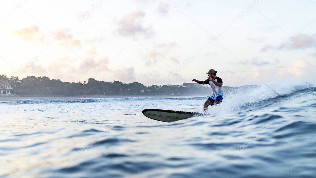 Young man swimming on surfing board in ocean in Bali, Indonesia.