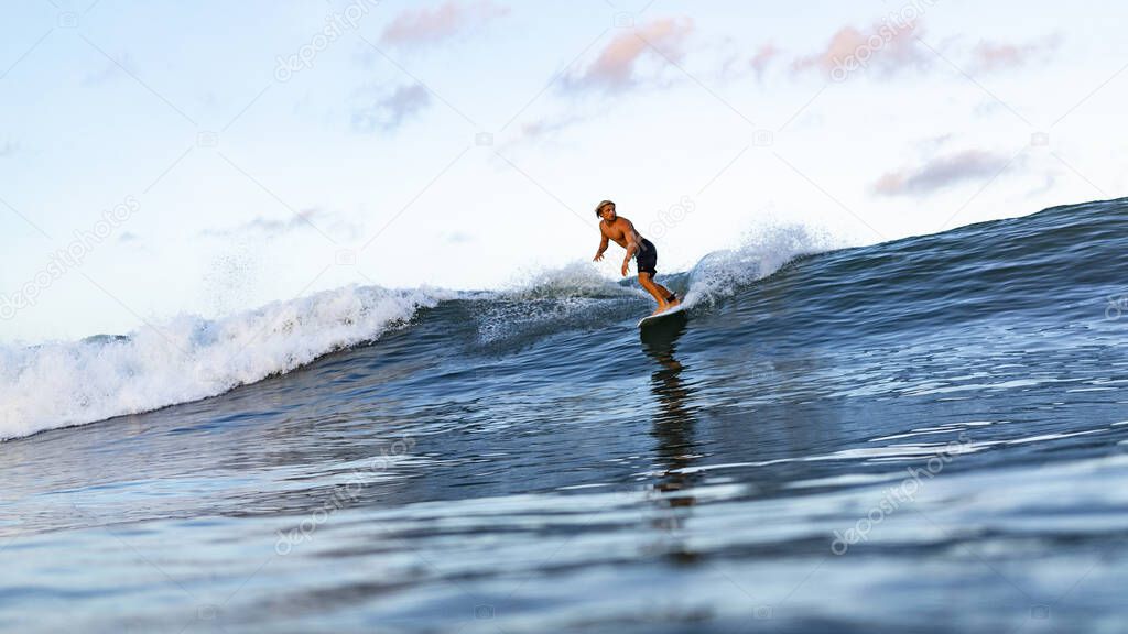 Young man swimming on surfing board in ocean in Bali, Indonesia.