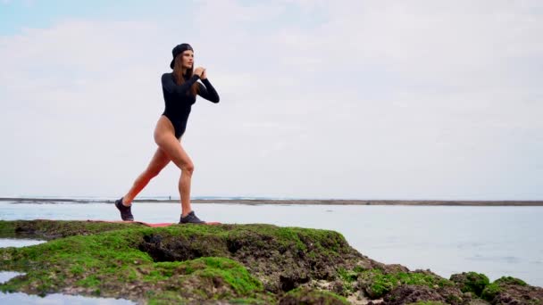 身穿泳衣的健康的年轻女子在海滩上做运动 — 图库视频影像
