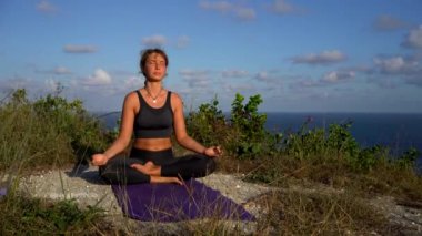 Fitness genç esmer kadın sabahları plajda yoga yapıyor.