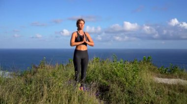 Genç kadın sabahları plajda yoga yapıyor.