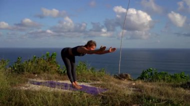 İnanılmaz kız sabahları sahilde yoga yapıyor. Dağların arkasında.