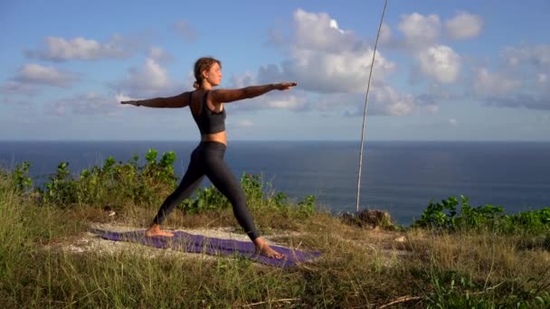素晴らしい女の子練習ヨガオンザビーチで朝の日に山の背景 — ストック動画