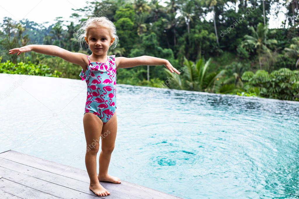little girl in swimsuit spend active time in the swimming pool in summer terrace villa