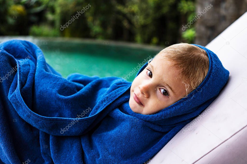 little girl in blue towel spend time in the swimming pool in summer terrace villa