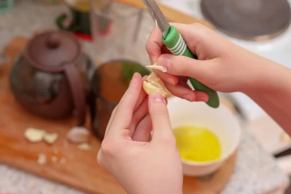 Kız sarımsağı soyup dilimliyor. Evde yemek pişirmek..