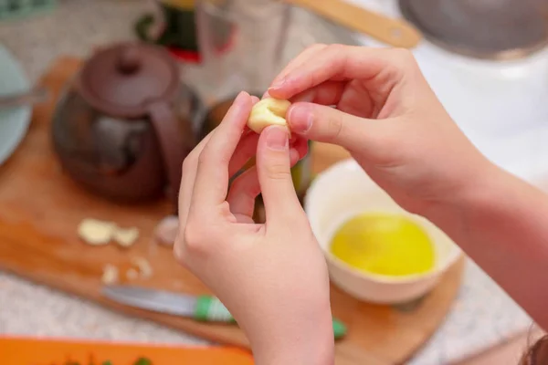 Kız sarımsağı soyup dilimliyor. Evde yemek pişirmek..