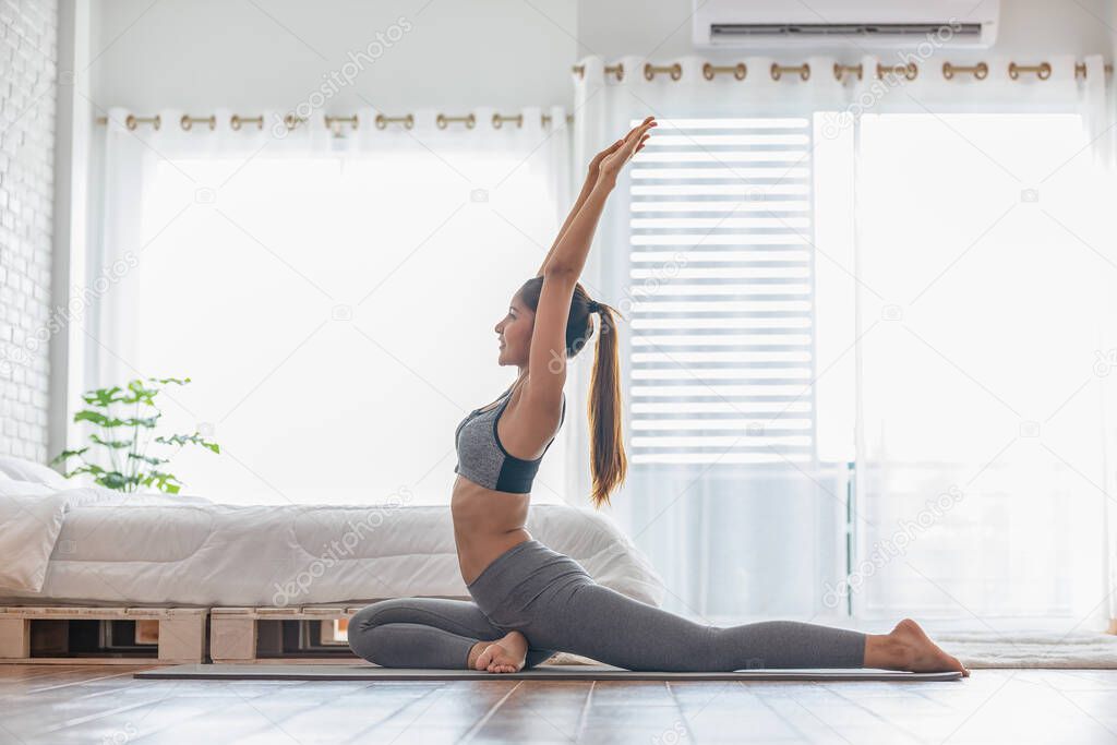 Attractive Asian woman practice yoga pigeon pose to meditation at home in bedroom after wake up in the morning Feeling so comfortable and relax,Yoga for Healthcare Concept