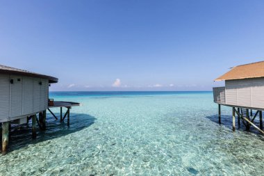 Maldivler 'deki tropikal ada tatil beldesinde su üzerinde güzel lüks villalar turkuaz deniz ve gün batımı, tatilde tatil beldesi yazın doğa ile dinlenin.