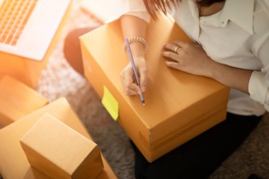 Laptop ile çalışan genç kadınların KOBİ girişimcisi ve evdeki sipariş çevrimiçi alışverişi için müşteri adresleri yazan Neşeli ve Mutlu, paket paketleri evde, başlangıç ve serbest konsepti ile birlikte