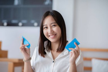 Çekici Asyalı güzel bir kadın yüz yağını temizlemek için temiz film kullanıyor. Yüzündeki yağı siliyor. Taze cilt için.