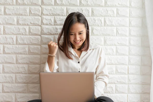 リビングルームに座っているアジアの若い女性の笑顔を祝うとソーシャルメディアやオンラインショッピングを使用するためのコンピュータのラップトップを使用してとても幸せと陽気な感じ — ストック写真