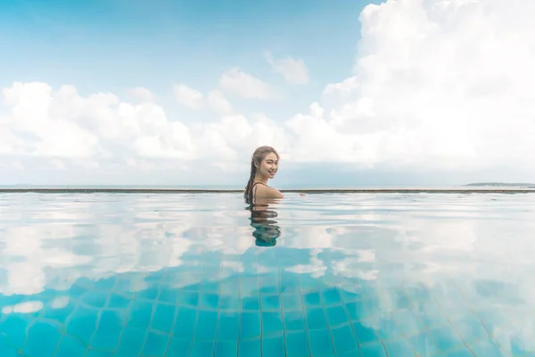 Vacations of Woman relax in tropical infinity pool above the beach with beautiful sea in Tropical island,Feeling comfortable and relax in holiday,Vacations Concept