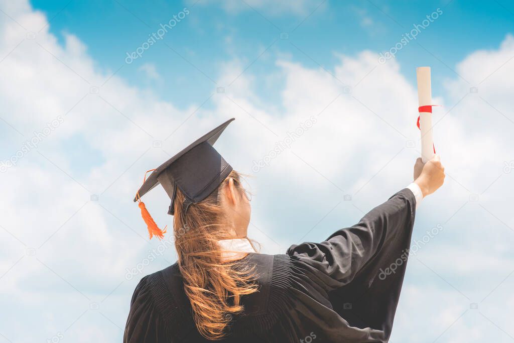 Graduate woman in cap and gown celebrating with certificate in her hand with blue sky background,Back of view,Summer Education Success Concept