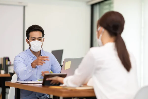 Business man and woman wearing face mask meeting and working together for discussion and brainstroming to get ideas or marketing solution with social distance due virus pandemic