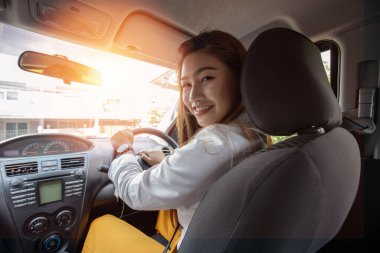 Dikiz aynasından güzel, çekici bir kadın arabada rahat rahat oturup gülümsüyor kendinden emin ve mutlu bir şekilde dalan bir araba, mutlu bir ulaşım konsepti.