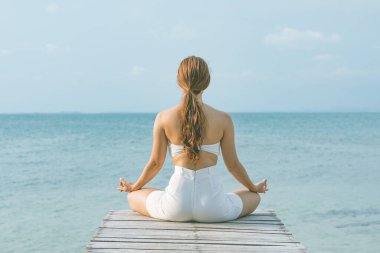 Bakış açısına göre kadın yoga nilüferleri yapıyor. Yaz tatili için rıhtımda meditasyon yapıyor. Mutluluk ve neşe dolu, tropik plajlarda seyahat ediyor, Tayland 'da tatil yapıyor ve dinleniyor.