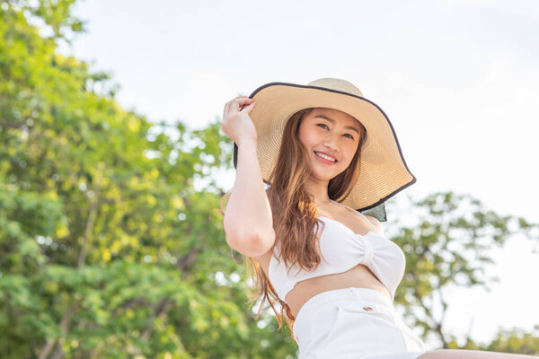 Attractive Asian young woman wearing white bikini smile enjoy with nature summer vacation on park feeling so happiness and cheerful,vacations and relaxation Concept
