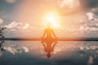 Yoga nilüferinde dinlenen güzel bir kadının, Tropikal adanın güzel deniziyle sahildeki havuzda poz vermesi tatilde kendini rahat ve rahat hissetmesi, tatil kavramı, sıcak bir ton.