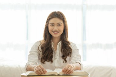 Güzel, çekici Asyalı kadın yatak odasında oturmuş öğrenme ve eğitim için kitap okuyor gülümseme ve olumlu düşünce çok mutlu ve rahat, Eğitim Konsepti