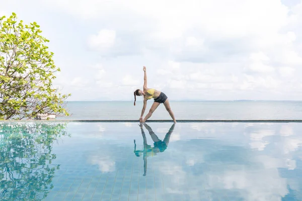 여성들은 트라이앵글을 연습하며 수영장에서 방학을 명상하고 해변을 여행하고 휴가와 컨셉트를 — 스톡 사진