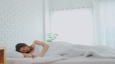 Pijama giyen güzel Asyalı kadın gözlerini kapar, gülümser ve tatlı rüyalar görür. Sabah yatak odasında rahat ve rahat hisseder. Sağlık ve Uyku Konsepti.