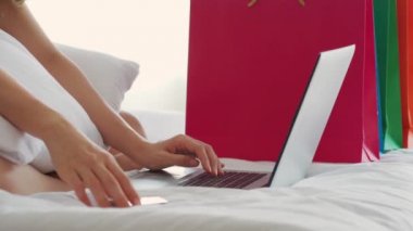 Sosyal medya ve internetten alışveriş yapmak için bilgisayar laptopu kullanan genç bir kadının ellerini kapat. Kredi kartını tut. Tatilde yatak odasında rahatla, yatak odasında yaşam tarzını düşün.