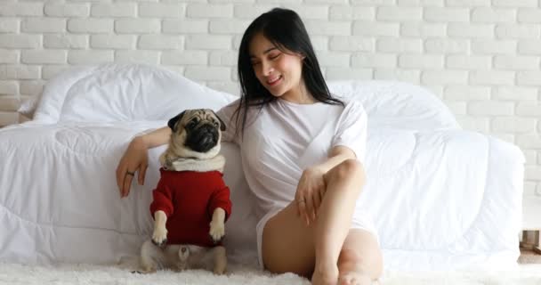 Gyönyörű ázsiai fiatal nő játszik vele kutya és mosolygós kutya mopsz fajta keres vicces és komoly arc a hálószobában érzés olyan boldog és pihentető, Kutya Barátság koncepció