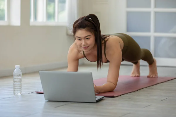 ラップトップ練習ヨガ板を探している魅力的なアジアの女性オンラインコース自宅で瞑想快適でリラックス — ストック写真