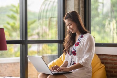 Bilgisayarlı dizüstü bilgisayarla çalışan Asyalı güzel bir kadın iş hayatında fikir ve gereksinim edinmeyi düşünüyor.