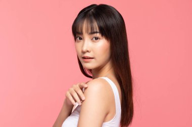 Genç ve güzel Asyalı kadın gülümsüyor yumuşak yanağa dokunuyor temiz ve taze tenli mutluluk ve neşe olumlu duygusal, pembe arka planda izole edilmiş güzellik kozmetik ve kaplıca konsepti