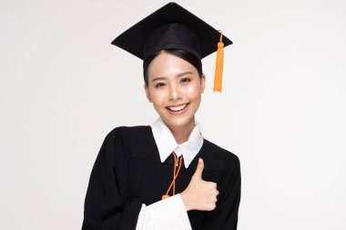Güzel, Çekici Asyalı kadın kep ve cübbe tebessümüyle mezun oldu. Gurur ve mutluluk dolu, beyaz arka planda izole edilmiş, Eğitim Başarı Konsepti.