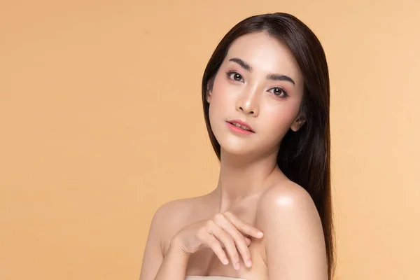 美丽的年轻亚洲女人一边摸着肩膀 一边又开心又快乐 有着健康的洁净而新鲜的皮肤 有着米色的背景 美容美感 — 图库照片