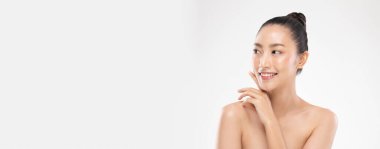 Güzel Asyalı bir kadının yumuşak yanaklı gülüşüne dokunduğu mutlu, neşeli, olumlu duygusal, beyaz arka planda soyutlanmış güzellik ve kozmetik anlayışı.