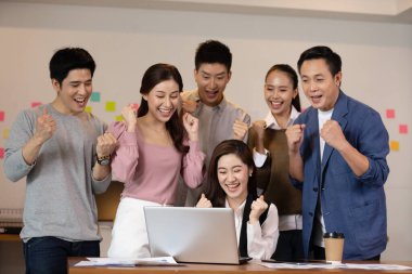 Birlikte çalışan bir grup genç Girişim çalışanı dizüstü bilgisayara bakıyorlar ve başarılı bir şekilde kutluyorlar. İş Kuruluşu Çeşitliliği Beyin Fırtınası Konsepti 'nde çalışıyorlar.