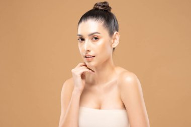 Güzel Cazibeli kadın temiz ve taze tenli yanak tebessümüne dokunuyor. Mutluluk ve neşe, olumlu duygusal, bej arka planda izole edilmiş, güzellik kozmetiği ve kaplıca tedavisi.