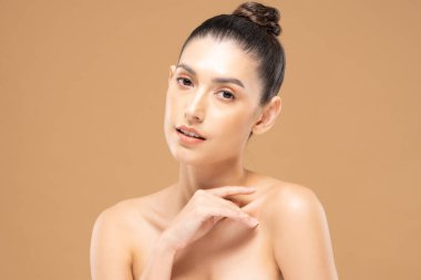 Güzel Cazibeli kadın omuzlarına dokunuyor temiz ve taze tenli gülümsüyor mutluluk ve neşe olumlu duygusal, bej arka planda izole edilmiş güzellik kozmetik ve kaplıca tedavisi konsepti