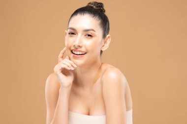 Güzel Cazibeli kadın temiz ve taze tenli yanak tebessümüne dokunuyor. Mutluluk ve neşe, olumlu duygusal, bej arka planda izole edilmiş, güzellik kozmetiği ve kaplıca tedavisi.