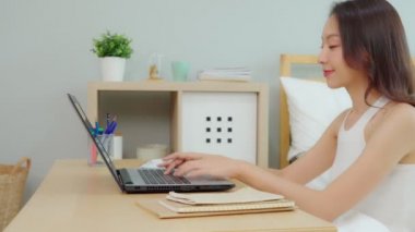 Bilgisayarlı dizüstü bilgisayarla çalışan güzel ve çekici Asyalı genç bir kadın. Evde işe başlamak için fikir ve gereksinim edinmeyi düşünüyor. Yani mutluluk, Business Startup Concept