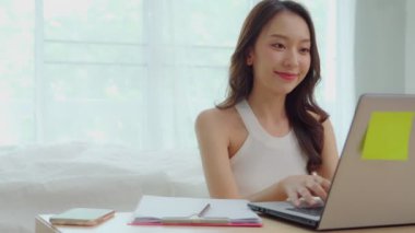 Evde online alışveriş için dizüstü bilgisayarla çalışan ve müşteriyle teslimat siparişi hakkında konuşan genç Asyalı kadınların iş kurumu